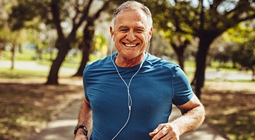 Senior man smiling while jogging outside