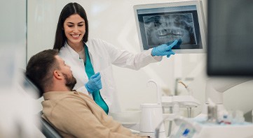 Dentist showing X-rays to patient in dental chair