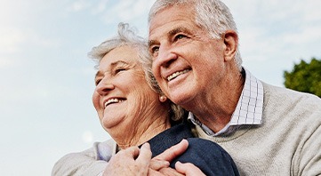 Senior couple smiling while hugging outside