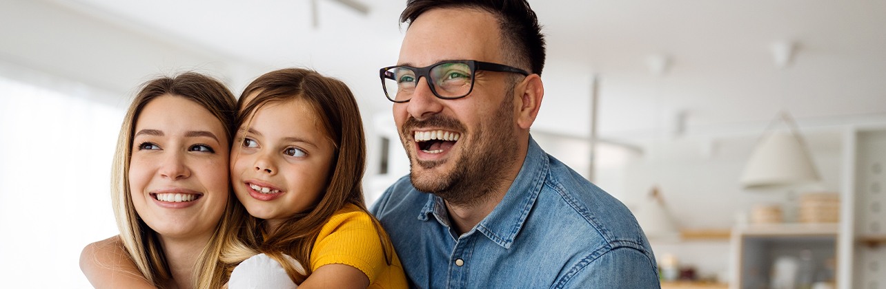 Parents and child smiling together after cosmetic dentistry