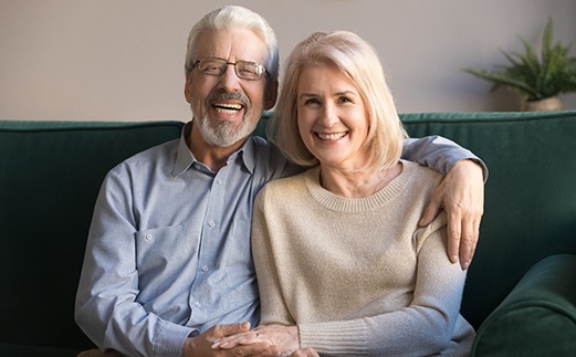 Man and woman holding hands and smiling on a green sofa