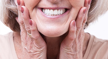 Nose down view of a woman with dentures holding her hands to her face