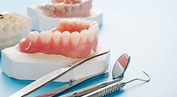 Set of dentures next to several dental instruments