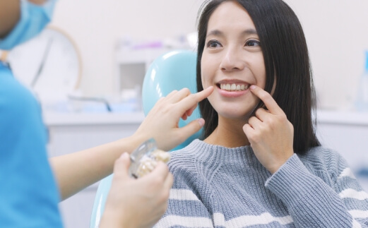 Woman pointing to smile after dental implant tooth replacement