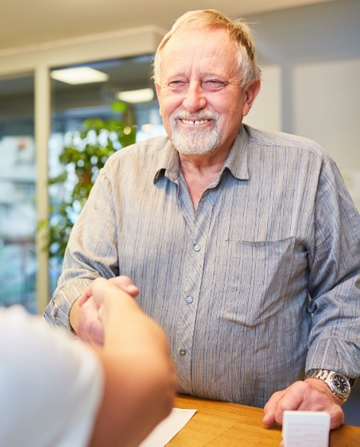 Dental patient shaking hands with team member after discussing dental insurance and financing