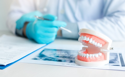 Dentist pointing to denture model