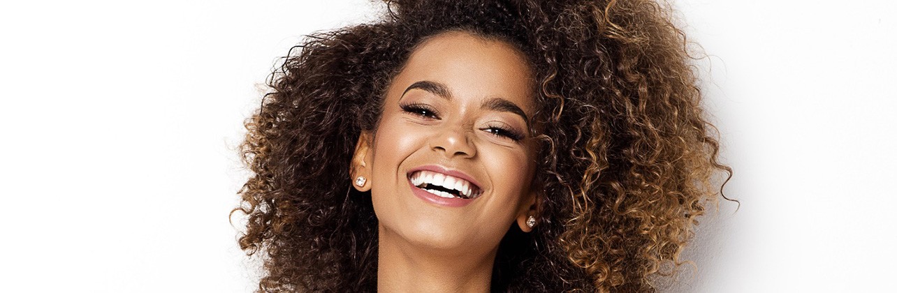 Woman with curly hair in white tank top smiling