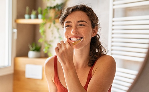 Girl in red tank top brushing teeth smiling