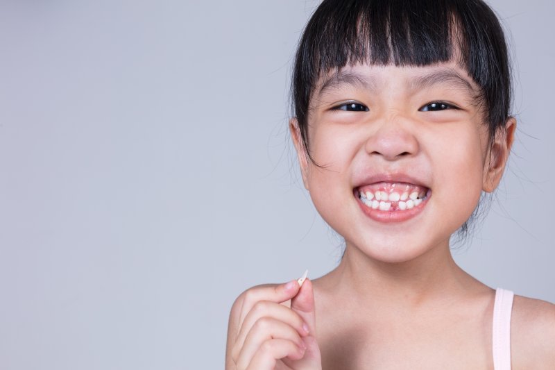 child holding a tooth that they’ve lost