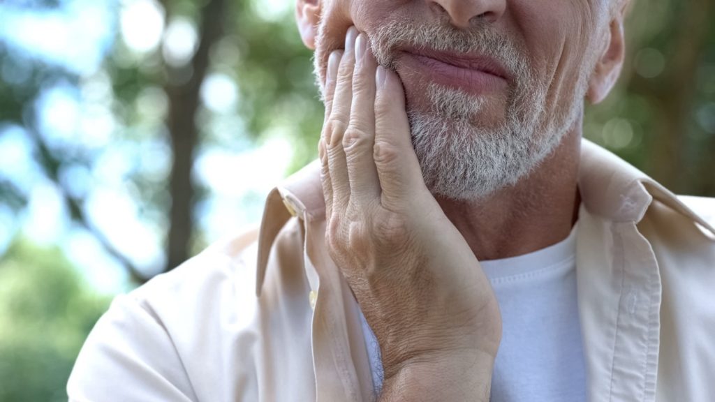 person with toothache holding cheek