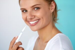 Woman smiling and holding whitening product. 